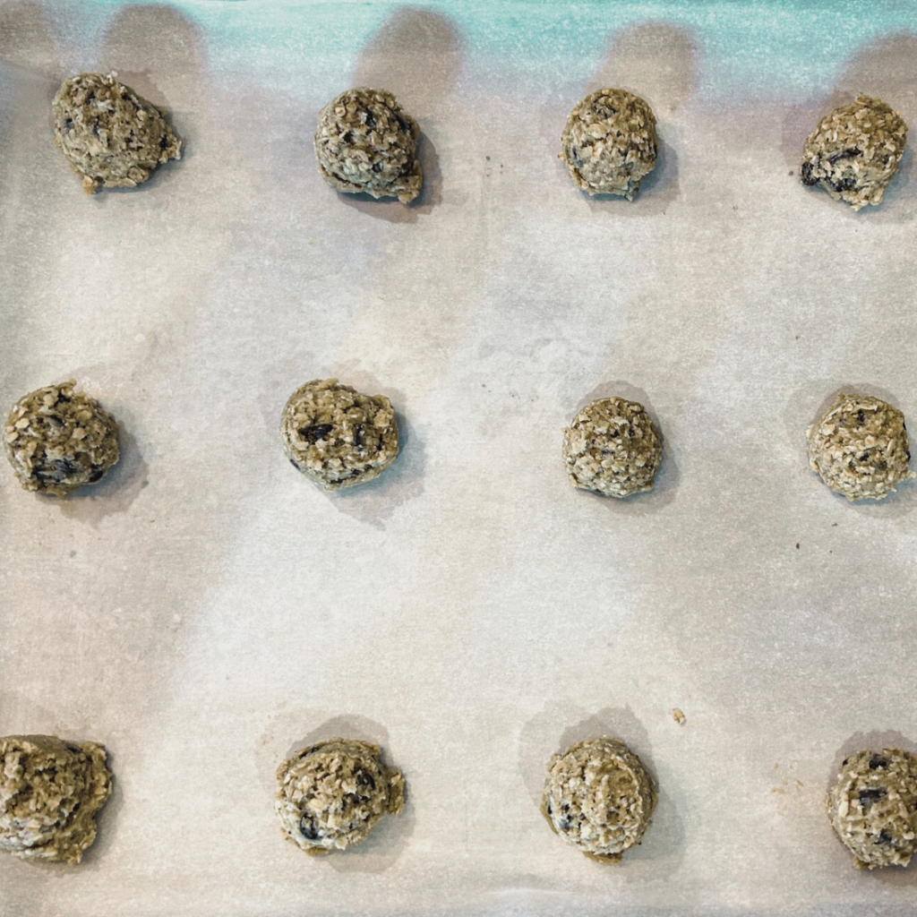 cookie dough balls lined in a row 4 by 3 on a parchment covered baking sheet