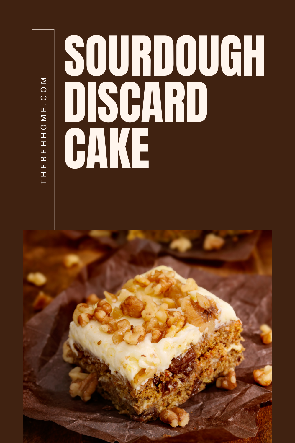 brown cake on dark brown cutting board with white cream cheese frosting sprinkled with toasted light brown walnuts